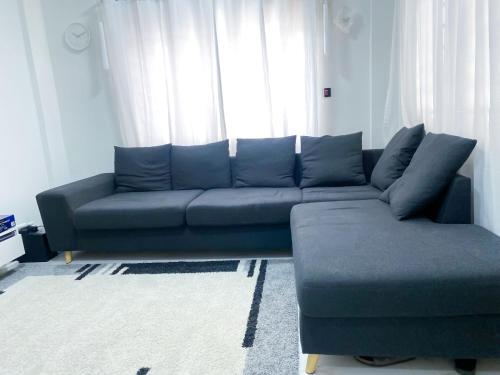 um sofá azul numa sala de estar com uma janela em Green-Hills Apartment em Kwabenya