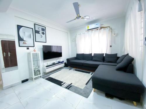 uma sala de estar com um sofá preto e uma televisão em Green-Hills Apartment em Kwabenya