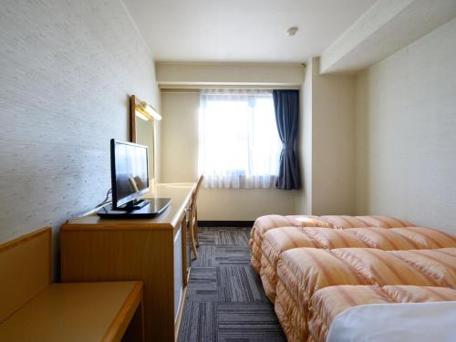 a hotel room with two beds and a television at Iga Ueno City Hotel in Iga