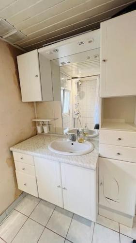 une salle de bain blanche avec un lavabo et un miroir dans l'établissement Maison de Renaud, à Eguisheim