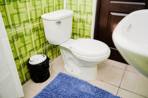 uma casa de banho com um WC branco e um tapete azul em 4 Elementos Hostal em San Juan La Laguna
