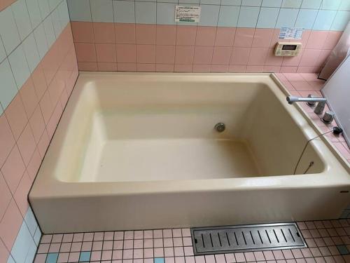 a white bath tub in a pink tiled bathroom at ilca イルカの家 -Kumano Kodo Nagaizaka- in Susami