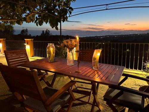 een houten tafel met kaarsen en bloemen op een balkon bij Relax House & Garden in Santa Luria