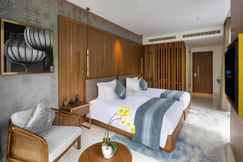 a bedroom with a bed and a couch and a tv at Wyndham Hoi An Royal Beachfront Resort & Villas in Hoi An