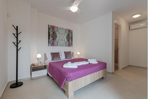 a bedroom with a bed with purple sheets and a painting at Costa Bianca Villas in Koilás