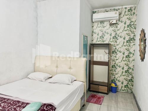 ein kleines Schlafzimmer mit einem Bett und einem Spiegel in der Unterkunft Lafa Park Syariah Mitra RedDoorz in Glonggong