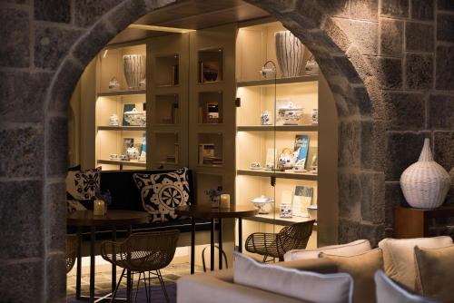 a room with a table and chairs and shelves with vases at Hotel Casa Hintze Ribeiro in Ponta Delgada