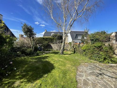 une cour avec un arbre et une maison dans l'établissement Maison de charme avec jardin clos, à 50m des commerces et proche plage, pour 8 personnes - FR-1-639-54, à Arzon
