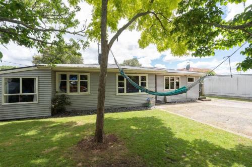 a house with a hammock hanging from a tree at Family-Friendly 5-Bedroom Home Near Uni & Hamilton Gardens - Sleeps 10 in Hamilton