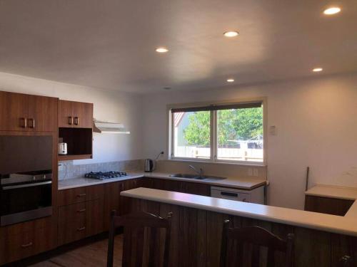 a kitchen with wooden cabinets and a large window at Family-Friendly 5-Bedroom Home Near Uni & Hamilton Gardens - Sleeps 10 in Hamilton