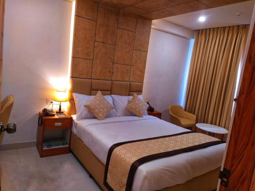 KānnangādにあるROYAL RESIDENCYのベッド、テーブル、ランプが備わるホテルルームです。