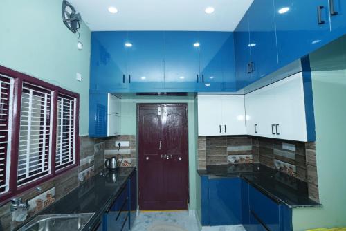 una cucina con armadi blu e una porta rossa di Katyayani Serenity - Your Premium Homestay a Bhadrachalam