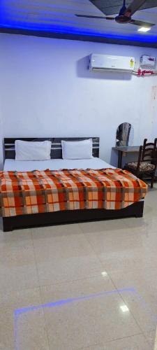 een slaapkamer met een bed met een oranje geruite deken bij Priya Prem peeth guest house ⁰ in Vrindāvan