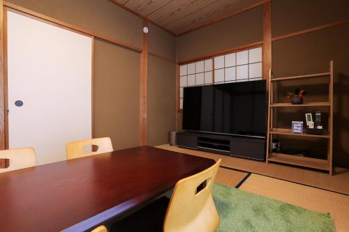a dining room with a table and a television at 貸切型の民泊です間取り2LDK無料駐車場有り全館完全禁煙です屋外喫煙所無し福井駅西口恐竜広場から徒歩約14分距離約1100m in Fukui