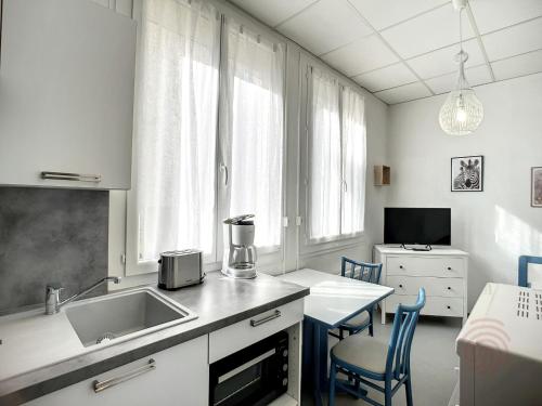 une cuisine avec un évier et une table avec des chaises dans l'établissement Studio idéal, proche Thermes, Lamalou les Bains, calme, animaux acceptés, wifi - FR-1-451-179, à Lamalou-les-Bains