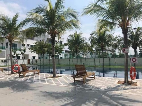 3 bancs en bois devant une piscine bordée de palmiers dans l'établissement Homestay, à Sitiawan