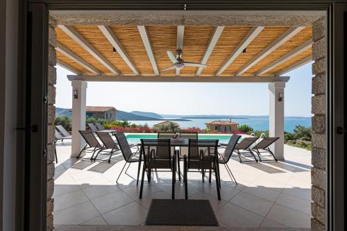 a patio with a table and chairs and a pool at Costa Bianca Villas in Koilás