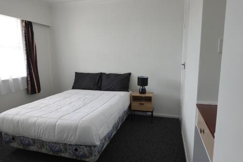 - une petite chambre avec un lit et une table de nuit dans l'établissement Ascot Lodge Motel, à Hamilton