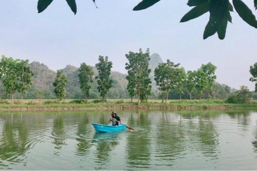 a man in a blue boat on a river at Baan Suan Khiriwong 2-BR Villa บ้านสวนคีรีวงศ์ in Khao Yoi