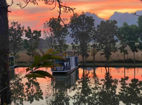 a house in the middle of a lake at sunset at Baan Suan Khiriwong 2-BR Villa บ้านสวนคีรีวงศ์ in Khao Yoi