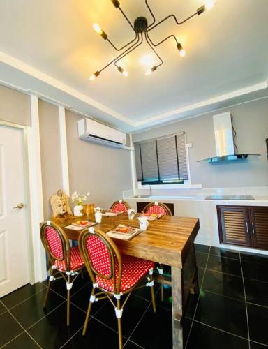 a kitchen with a wooden table with red chairs at Baan Suan Khiriwong 2-BR Villa บ้านสวนคีรีวงศ์ in Khao Yoi