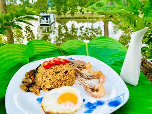 a plate of food with an egg and shrimp on a table at Baan Suan Khiriwong 2-BR Villa บ้านสวนคีรีวงศ์ in Khao Yoi