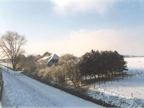 a house in the snow next to a fence at Holiday house on the Diek in Bockhorn