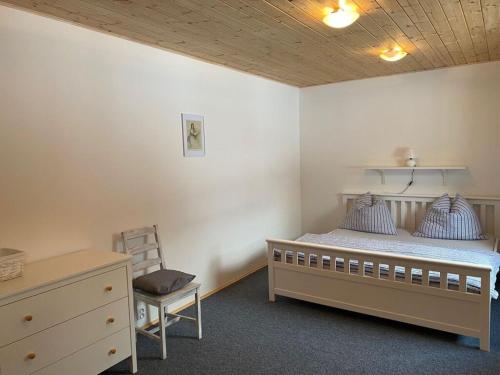 Český Jiřetín的住宿－Yellow House Modern Retreat，一间卧室配有一张床、一把椅子和一个梳妆台