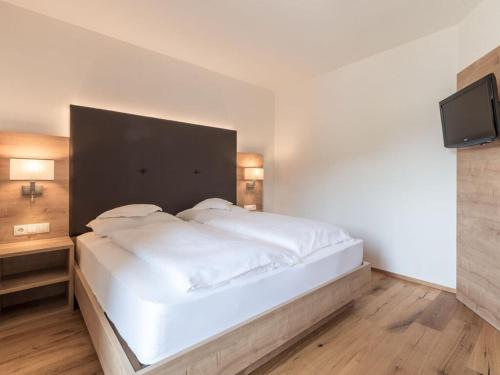 a bedroom with a large white bed with a flat screen tv at in het Aparthotel Panorama in Gais