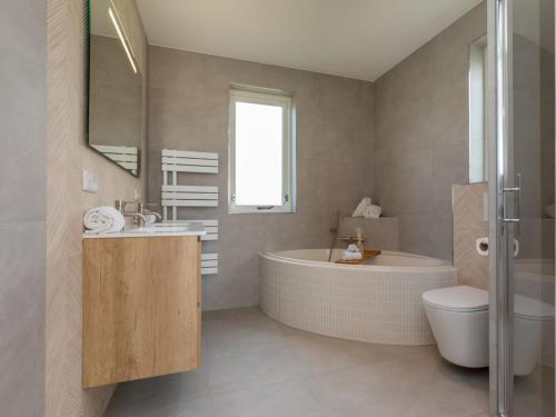 uma casa de banho com uma banheira, um lavatório e um WC. em Enjoy at "t Kusthuys em Zoutelande