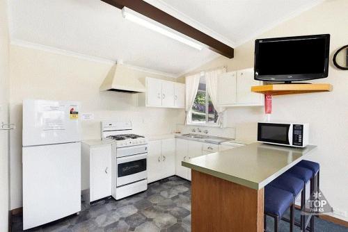 a kitchen with white appliances and a tv on the wall at Buckenderra Holiday Village in Rocky Plain