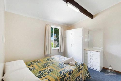a bedroom with a bed and a dresser and a window at Buckenderra Holiday Village in Rocky Plain