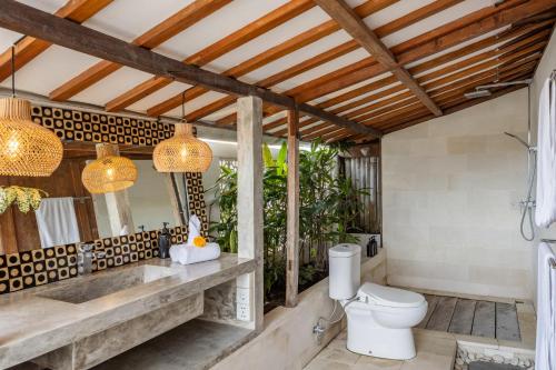 a bathroom with a toilet and a wooden ceiling at 5 Bedroom Entire Villa in Berawa Canggu in Dalung