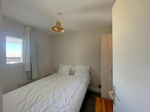 um pequeno quarto com uma cama com lençóis brancos e uma janela em Appartement Saintes-Maries-de-la-Mer, 2 pièces, 4 personnes - FR-1-475-111 em Saintes-Maries-de-la-Mer
