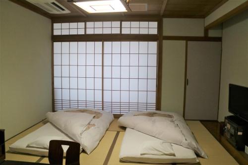 a room with two beds in front of a window at ホテル晴山 in Chikuma