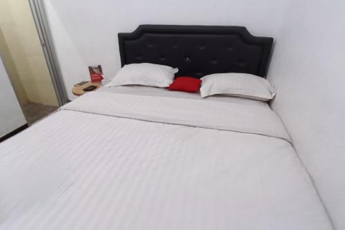 Klaten的住宿－OYO 93885 D'harjo Guesthouse，一张带黑色床头板的白色床和两个枕头