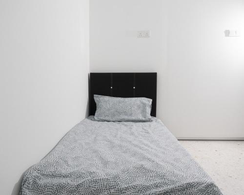 a bed with a gray blanket and a black headboard at Miami Beach Hotel in Batu Ferringhi