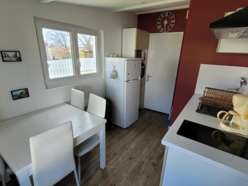 Il comprend une cuisine équipée d'une table blanche et d'un réfrigérateur blanc. dans l'établissement Charmante maisonnette rénovée à Notre-Dame-de-Monts, avec jardin, proche plage – 4 pers, animaux admis - FR-1-540-231, à Notre-Dame-de-Monts