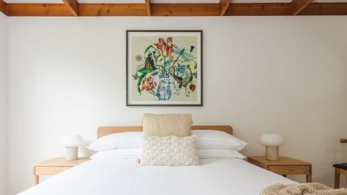 a bedroom with a white bed with a picture on the wall at Nantucket Cottage in Flinders in Flinders
