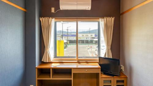 a room with a window and a desk with a television at Tabist Oyado Chitose in Kazuno