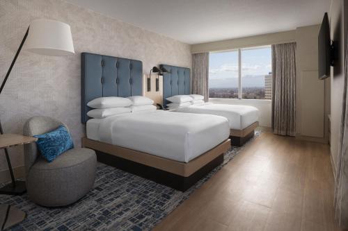 a hotel room with two beds and a chair at San Jose Marriott in San Jose