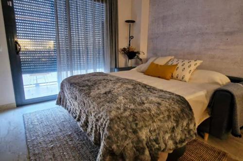 a bedroom with a large bed and a large window at L'Ampolla, sol y mar in L'Ampolla