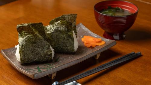 a plate with a piece of bread and a bowl of soup at Tabist Oyado Chitose in Kazuno