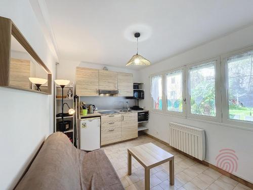 une cuisine avec des placards en bois et une table dans l'établissement Charmant T2 avec terrasse Sud, parking, WiFi, animaux acceptés - proche thermes et centre Lamalou - FR-1-451-192, à Lamalou-les-Bains