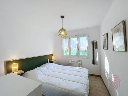 une chambre avec deux lits blancs et une fenêtre dans l'établissement Charmant T2 avec terrasse Sud, parking, WiFi, animaux acceptés - proche thermes et centre Lamalou - FR-1-451-192, à Lamalou-les-Bains