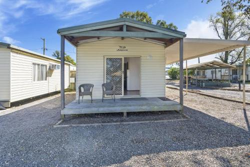 un petit bâtiment avec une chaise sur une terrasse couverte dans l'établissement Coachstop Caravan Park, à Maitland
