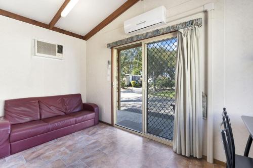 a living room with a couch and a sliding glass door at Coachstop Caravan Park in Maitland