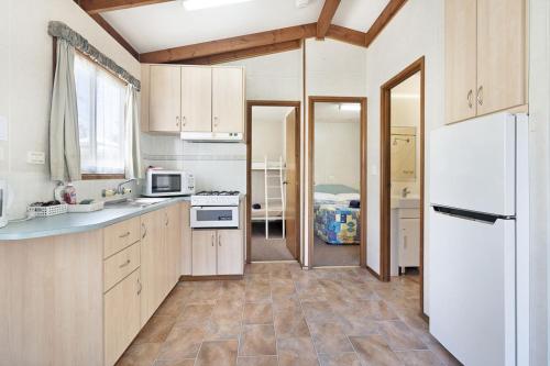 - une cuisine avec des placards en bois et un réfrigérateur blanc dans l'établissement Coachstop Caravan Park, à Maitland