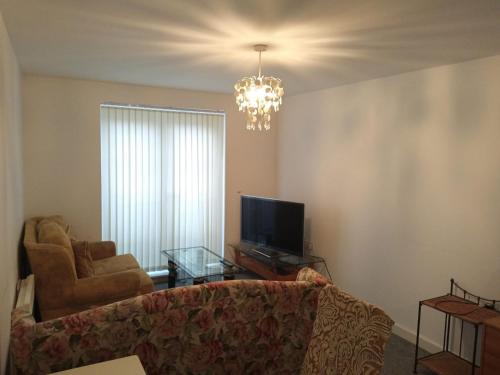 sala de estar con sofá, TV y lámpara de araña en The Flat, en Monmore Green