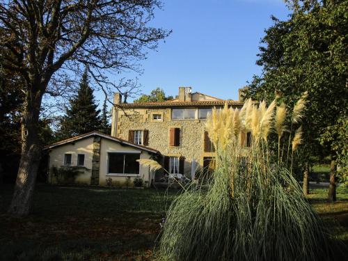 une vieille maison en pierre avec des arbres et de l'herbe dans l'établissement Domaine De Luzenac, à Fa